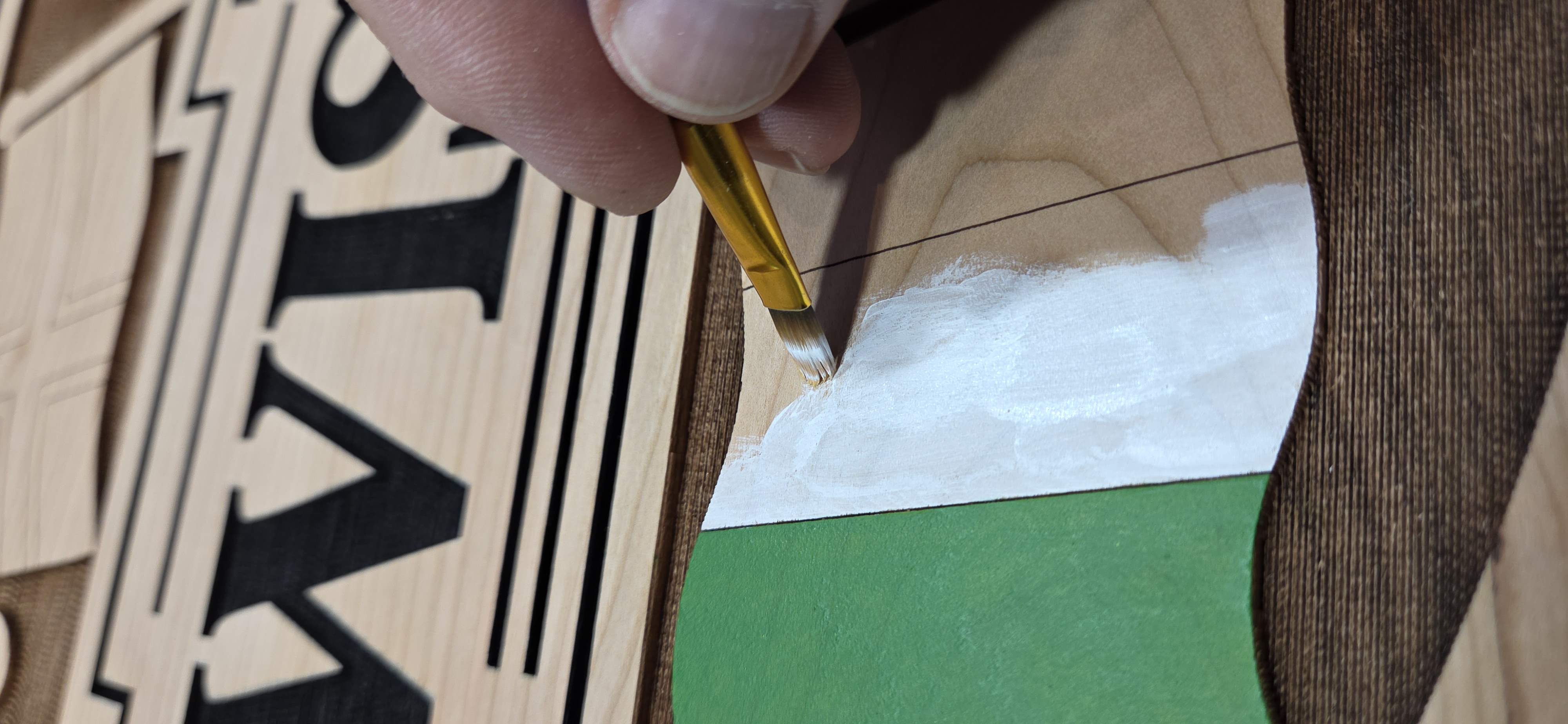 Hand painting details on the Wisloffs family heritage sign in the Kennedy Laser Works workshop